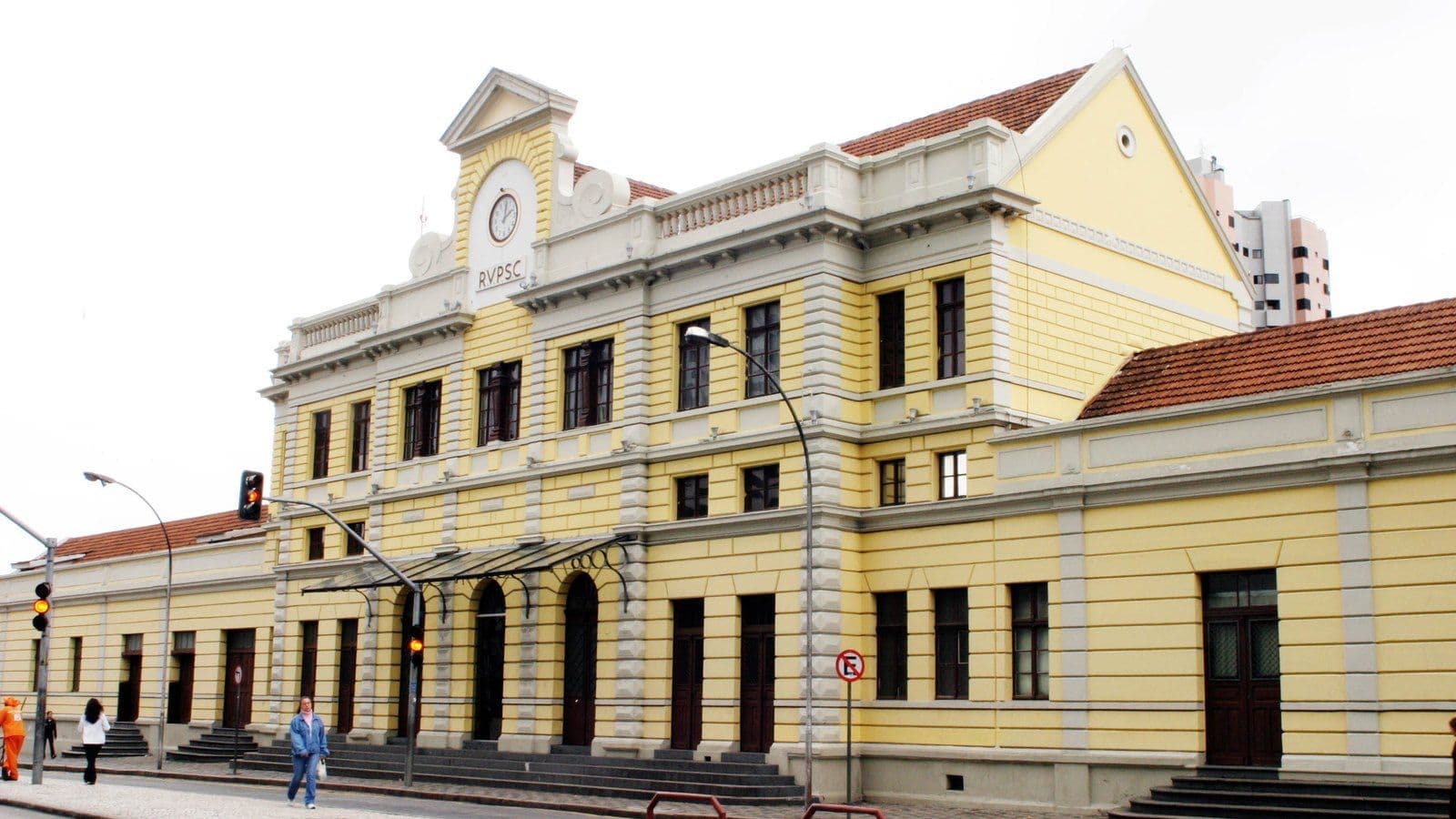 Fachada amarela da antiga estação ferroviária de Curitiba, com relógio no frontão e portas em arco, onde fica o Museu Ferroviário